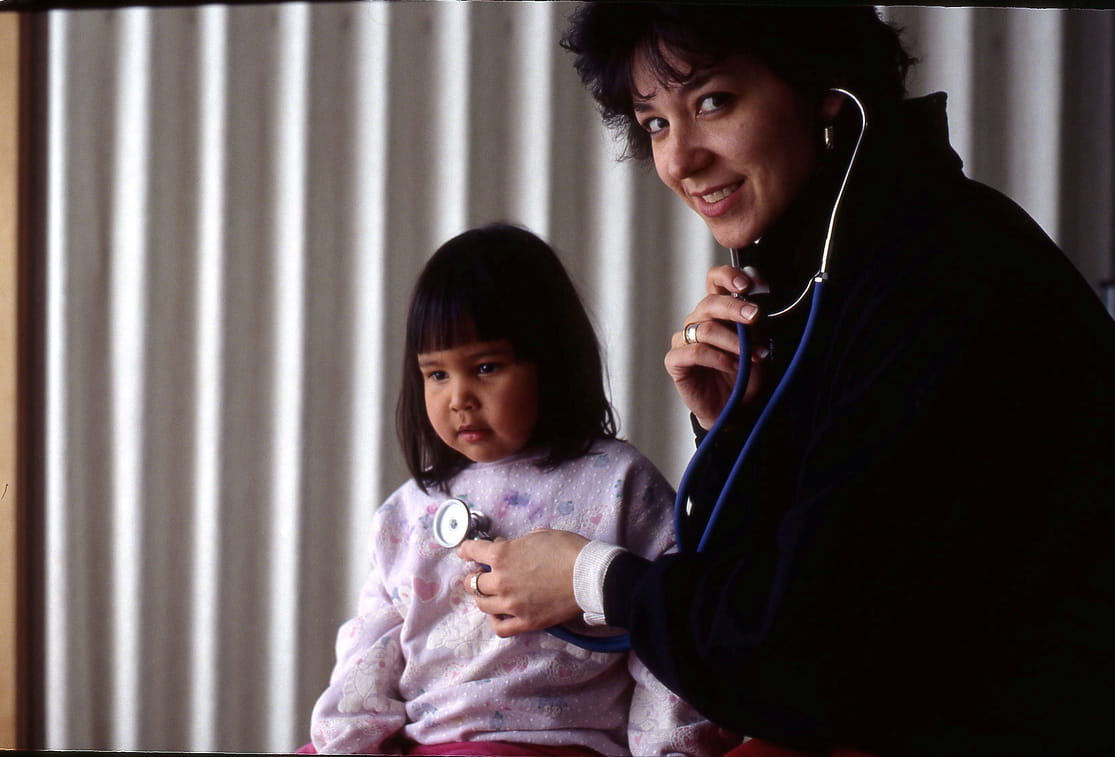 Indigenous child receiving health care from a doctor using a stethoscope